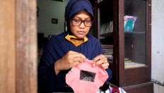 Dwi stitches the clear mask before sewing it with a machine. JP/Arnold Simanjuntak