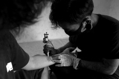 Kadek draws a pattern on the arm of a customer. JP/M Azis Dicky