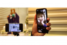 Father Ginting (left) leads a funeral service at Dharmais funeral home in West Jakarta on May 16. It is a family-only event. Friends and colleagues participate using a livestreaming application. (right) Laia Elora Permadi, who lives in Bali, watches as family members close her grandmother's coffin. JP/Seto Wardhana