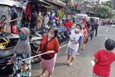 Hundreds of people get in line to buy rice and chicken for Rp 3,000 (US 20 cents) per package in Bandung, West Java, on May 15. They are required to hold a stick to maintain a safe distance. JP/Arya Dipa