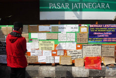 A visitor looks at a merchant information board on May 15 at East Jakarta’s Jatinegara Market, which is temporarily closed due to the city’s large-scale social restrictions. The board contains the phone numbers of market merchants who have continued to offer their services. JP/Dhoni Setiawan