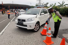 A police officer orders a car’s driver to make a U-turn at the Cikupa toll gate in Tangerang, Banten, on Wednesday May 27, to prevent the car from entering Jakarta. The police only grant access to travelers who have Jakarta Exit and Entry Permit (SIKM). JP/Dhoni Setiawan