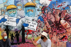 Residents chat in front of a COVID-19-themed mural in Pondok Pondok Aren, South Tangerang, Banten, on May 21. The mural, created by the residents, aims to show support and appreciation for the struggle of medical personnel who are at the forefront in the battle against the virus pandemic. JP/Seto Wardhana