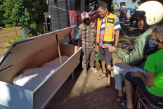 A Jakarta Public Order Agency (Satpol PP) officer shows a mockup coffin and corpse to a man in an orange vest, who violated the social distancing policy, at the entrance of Pondok Ranggon public cemetery in East Jakarta on May 25. JP/P.J.Leo