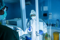 A laboratory staff member hands out swab specimens that have been mixed with reagents to be analyzed in a real-time polymerase chain reaction (PCR) machine.  JP/Agung Parameswara