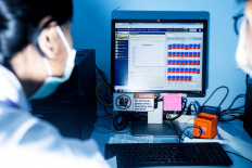 Biomolecule scientist Erly Sintya (right) and a laboratory staff worker read the analysis generated from the real-time polymerase chain reaction (PCR) machine. The test result is based on the cycle threshold value (Ct value) of each specimen. The sample is declared positive for SARS-CoV-2, the virus that causes COVID-19, if it has a Ct value below 40. JP/Agung Parameswara