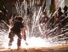 A firecracker thrown by protesters explodes under police one block from the White House on May 30, 2020 in Washington DC, during a protest over the death of George Floyd, an unarmed black man, who died after a Minneapolis 
police officer kneeled on his neck for several minutes. - Clashes broke out and major cities imposed curfews as America began another night of unrest Saturday with angry demonstrators ignoring warnings from President Donald Trump that his government would stop violent protests over police brutality "cold." AFP/Andrew-Caballero Reynolds 
