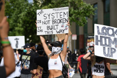 Demonstrators hold signs in front of police on June 1, 2020 in the Van Nuys area of Los Angeles, California during a protest over the death of George Floyd. - Major US cities -- convulsed by protests, clashes with police and looting since the death in Minneapolis police custody of George Floyd a week ago -- braced Monday for another night of unrest. More than 40 cities have imposed curfews after consecutive nights of tension that included looting and the trashing of parked cars. AFP/Robyn Beck