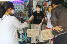 A shop owner serves customers on Monday at the entrance of his lighting and electrical store on Jl. Pamulang Raya in South Tangerang, Banten. JP/Dhoni Setiawan