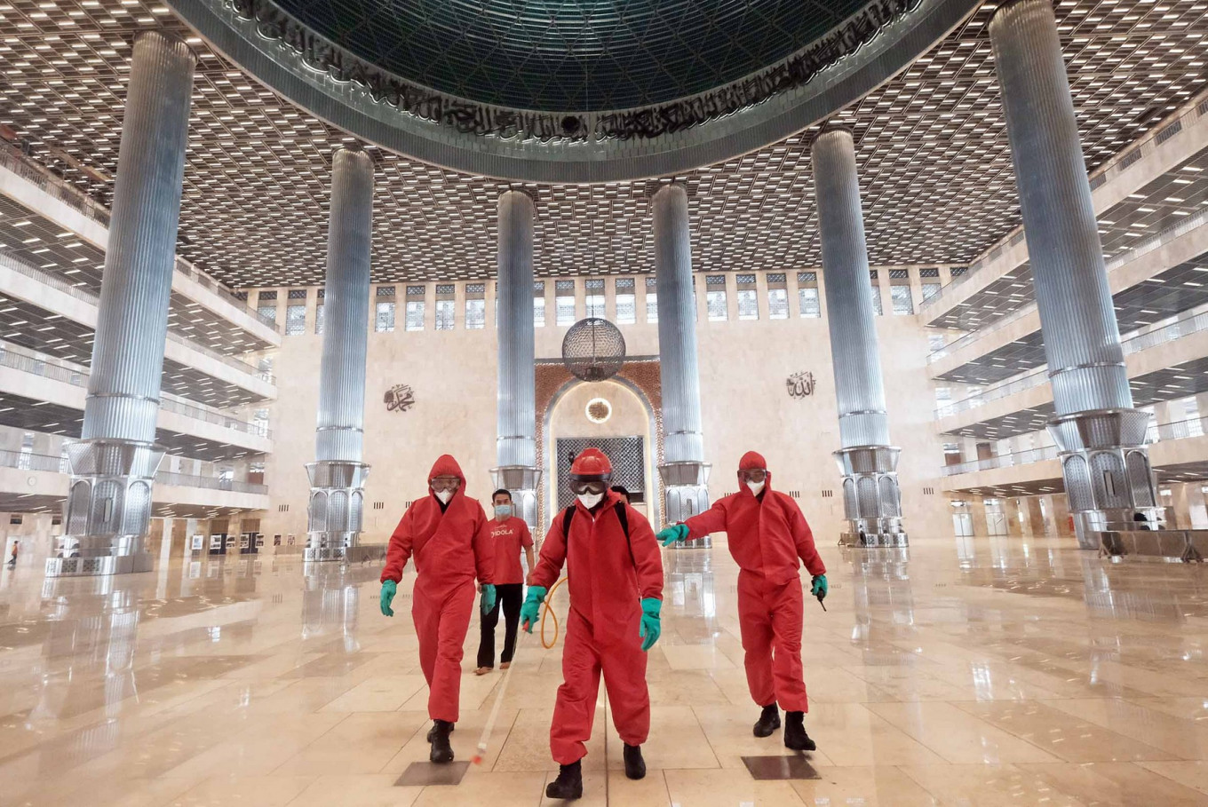 Fire and Rescue Agency personnel wear bright red hazmat suits as they disinfect Istiqlal Mosque in Central Jakarta on Wednesday, in preparation for gradually transitioning the capital out of the large-scale social restrictions (PSBB) over the month of June. JP/Donny Fernando