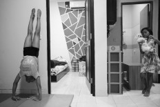 Ave does a handstand while her little sister, Agda, plays with their dog. JP/Toto Santiko Budi