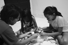 After training, Ave and Agda help their mother, Eta, peel garlic. JP/Toto Santiko Budi