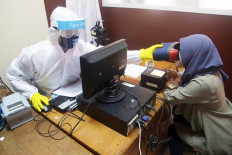 A civil registration officer in full PPE takes an optical scan of a woman on Tuesday to gather biometric data for issuing an electronic identity card at the Population and Civil Registration office in Pondok Aren, South Tangerang, Banten. JP/Wendra Ajistyatama