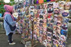 A face mask vendor arranges her display rack on Wednesday near the Bogor regency office in Pakansari, Bogor, West Java. The printed masks, which bear a variety of designs from soccer club logos to pictures of mustached mouths, and even the mouth of Stephen King’s Pennywise the Clown, cost from Rp 5,000 (35 US cents) to Rp 15,000 each. JP/P.J. Leo