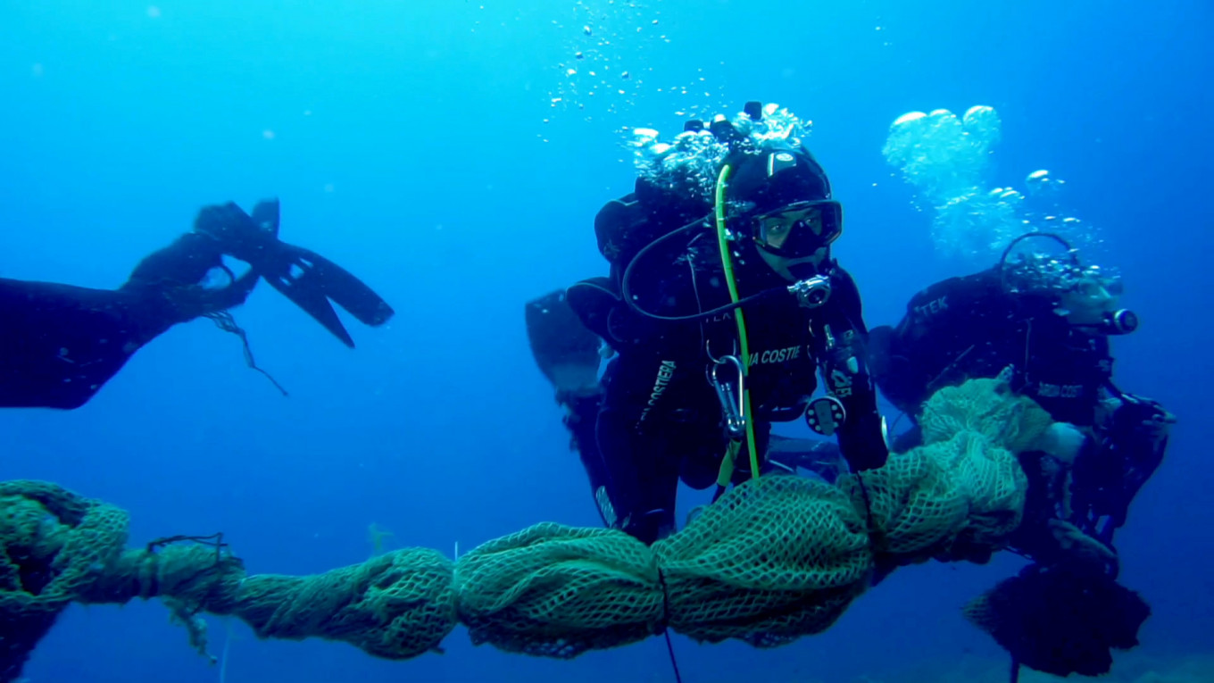 Italian Coast Guard divers collect and remove abandoned fishing nets from the sea off the coast of Lazio during a study on the health of Italy's seas and improvements to marine life due to a lack of human activities during the coronavirus disease (COVID-19) lockdown, in this still picture taken from video, in June 2020.