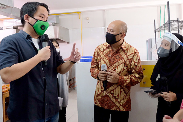 Down to business: Cooperatives and Small and Medium Enterprises Minister Teten Masduki (center) listens to an explanation from Co-CEO of Gojek Andre Soelistyo (left) on joint business operations between Gojek and members of micro, small and medium culinary business units in Bintaro, South Jakarta, on Thursday.