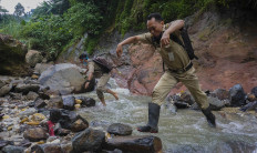 SMP 4 Bawang principal Mulud Sugito and teacher Wiyata Bhakti cross a river to reach their students’ houses. JP/Harviyan Perdana Putra