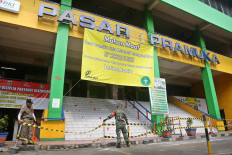 A Public Order Agency (Satpol PP) officer and a soldier cordon off Pramuka Market in Jakarta on July 12. The market was closed from July 11 to July 13 after a vendor there tested positive for COVID-19. JP/Wendra Ajistyatama