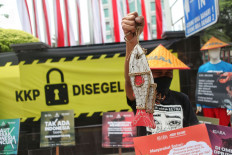 An activist from the People’s Coalition for Fisheries Justice (KIARA) holds up wooden fish during a protest in front of the Maritime Affairs and Fisheries Ministry in Jakarta on July 13. The protest was held against the ministry’s recent regulations that allow the export of lobster seeds and the use of cantrang (seine nets) for fishing. JP/Seto Wardhana