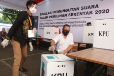 An election official helps a voter with a disability take part in a simulation of the 2020 simultaneous regional elections in the front yard of the General Elections Commission (KPU) headquarters on July 22. The KPU implemented COVID-19 protocols while holding the voting simulation. JP/Dhoni Setiawan

