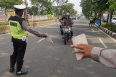 Police officers stop motorcyclists during the Patuh Jaya traffic operation in Jakarta on July 23. The operation, which runs from July 23 until August, involves 1,807 joint personnel from the Indonesian Military, the National Police, the Jakarta Public Order Agency and Jakarta Transportation Agency.  JP/Wendra Ajistyatama