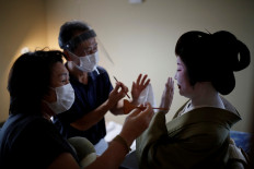 Mitsunaga Kanda, a makeup artist and Yurie Hatanaka, a wig stylist, wear protective face masks and face shields as they work on Tokijyo Hanasaki, a jiutamai dancer, before he dances for a film being made that is supported by the Tokyo Metropolitan government in order to support artists during the coronavirus disease (COVID-19) outbreak, at a studio in Tokyo, Japan, June 29, 2020. "Every single one of my events has been cancelled", said Kanda. "We touch their skin and their face, all over, and while we don't talk we're very close - something we're very aware of now." Reuters/Kim Kyung-Hoon 
