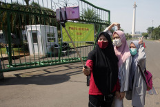 A group of girls take a selfie in front of the gate of the National Monument in Central Jakarta on July 26. Jakarta Deputy Governor Ahmad Riza Patria said the tourist site would remain closed to visitors as it was undergoing rearrangements amid the epidemic. JP/Wendra Ajistyatama