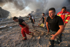 Firefighters evacuate a wounded man from the scene of an explosion at the port in Beirut on August 4, 2020. - Two huge explosion rocked the Lebanese capital Beirut, wounding dozens of people, shaking buildings and sending huge plumes of smoke billowing into the sky. Lebanese media carried images of people trapped under rubble, some bloodied, after the massive explosions, the cause of which was not immediately known. AFP/Anwar Amro