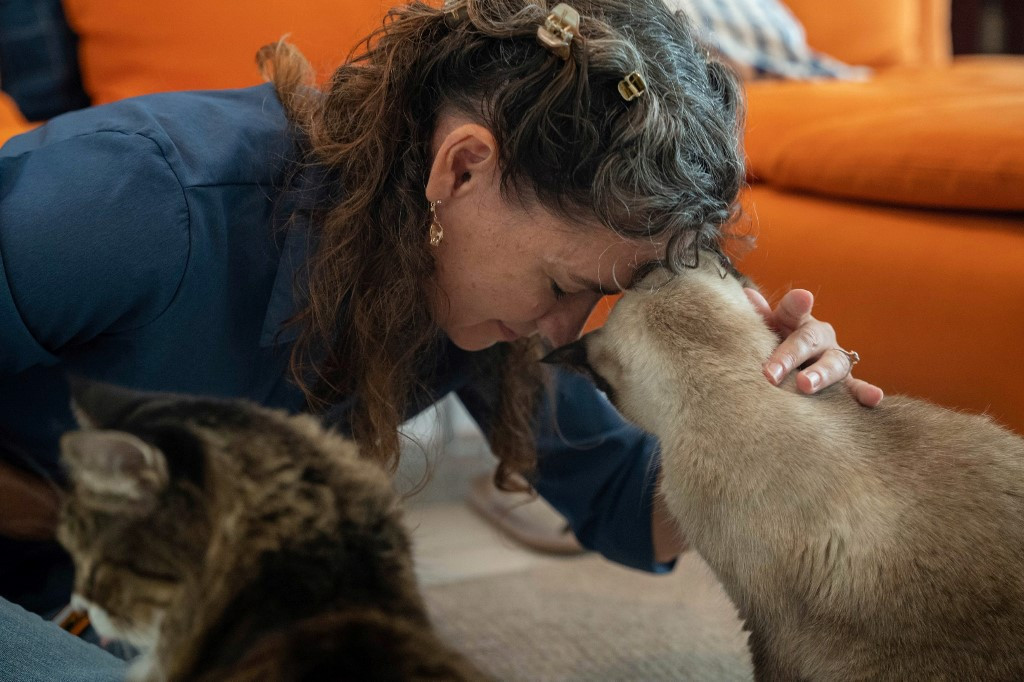 In this picture taken on August 4, 2020, cat consultant Briganne Carter touches her forehead to her Siamese cat Prudence at her home in the outlying island of Cheung Chau in Hong Kong. 