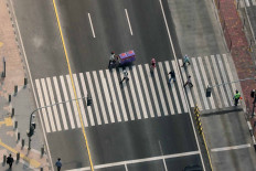 Pedestrians cross Jl. MH Thamrin in Central Jakarta on Aug. 3. The business district remains relatively empty as many workers continue to work from home. JP/Dhoni Setiawan
