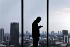 A Muamalat Bank employee uses his smartphone at work at the Muamalat Tower in Jakarta on Sept. 22. Finance Minister Sri Mulyani projects that Indonesia’s economy will contract between 0.6 to 1.7 percent this year due to the COVID-19 pandemic. JP/Seto Wardhana.