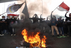 Smoke signal: Protesters wave the Indonesian flag before a burning tire on Wednesday, October 7.2020 during a protest near the Pasar Rebo flyover in East Jakarta. Similar scenes took place in major cities nationwide during the three-day demonstrations to protest the newly passed Job Creation Law. JP/P.J. Leo