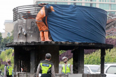 An officer from the city’s Public Facility Maintenance Agency (PSSU) covers the upper part of a burned police station in the Tugu Tani area of Central Jakarta, on Oct. 9. Some public facilities were damaged as the result of clashes between the police and protesters during a rally against the Job Creation Law in Jakarta. JP/Dhoni Setiawan