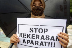 An activist from the Alliance Refusing to Forget (Aliansi Menolak Lupa) stands under a black umbrella in a silent protest in front on the Tugu Proklamasi (Proclamation Monument) in Central Jakarta, on Oct. 15. The activists protested against the police’s repressive actions toward protesters during a series of rallies against the newly passed Job Creation Law. They called on the police to release detainees. JP/Wendra Ajistyatama