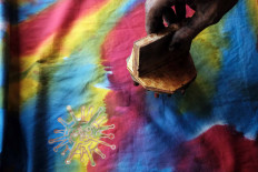Nurohmad, 45, stamps a COVID-19 batik motif on a piece of fabric in Panggungharjo Bantul, Yogyakarta, on Oct. 11. The COVID-19 motif fabric sells for Rp 100,000 (US$6.80) to Rp 500,000 depending on the fabric’s quality. JP/Donny Fernando