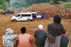 Distance mourning: Family members watch as gravediggers bury the body of a COVID-19 patient at the Pondok Ranggon cemetery in East Jakarta on Sept.14. At the time, space designated at the cemetery for COVID-19 victims was quickly filling up. JP/P.J.Leo